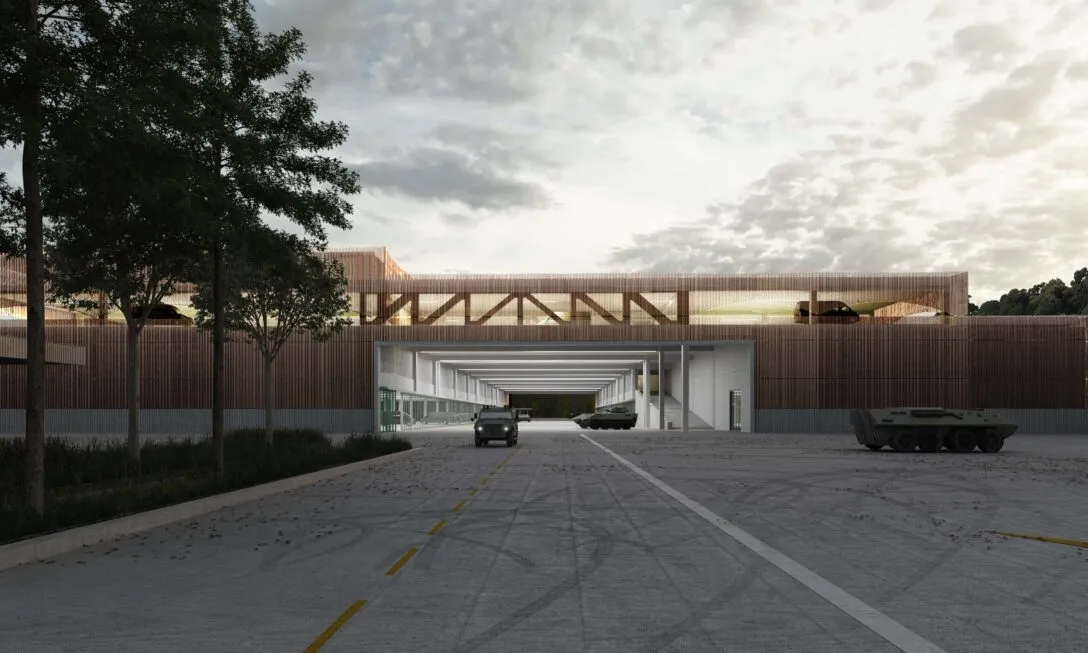 Langes Gebäude mit einer grossen Öffnung. Daraus fährt ein Militärfahrzeug