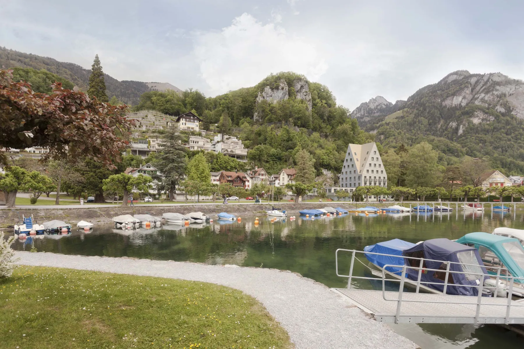See mit vielen Booten am Ufer und einem Kiesweg 