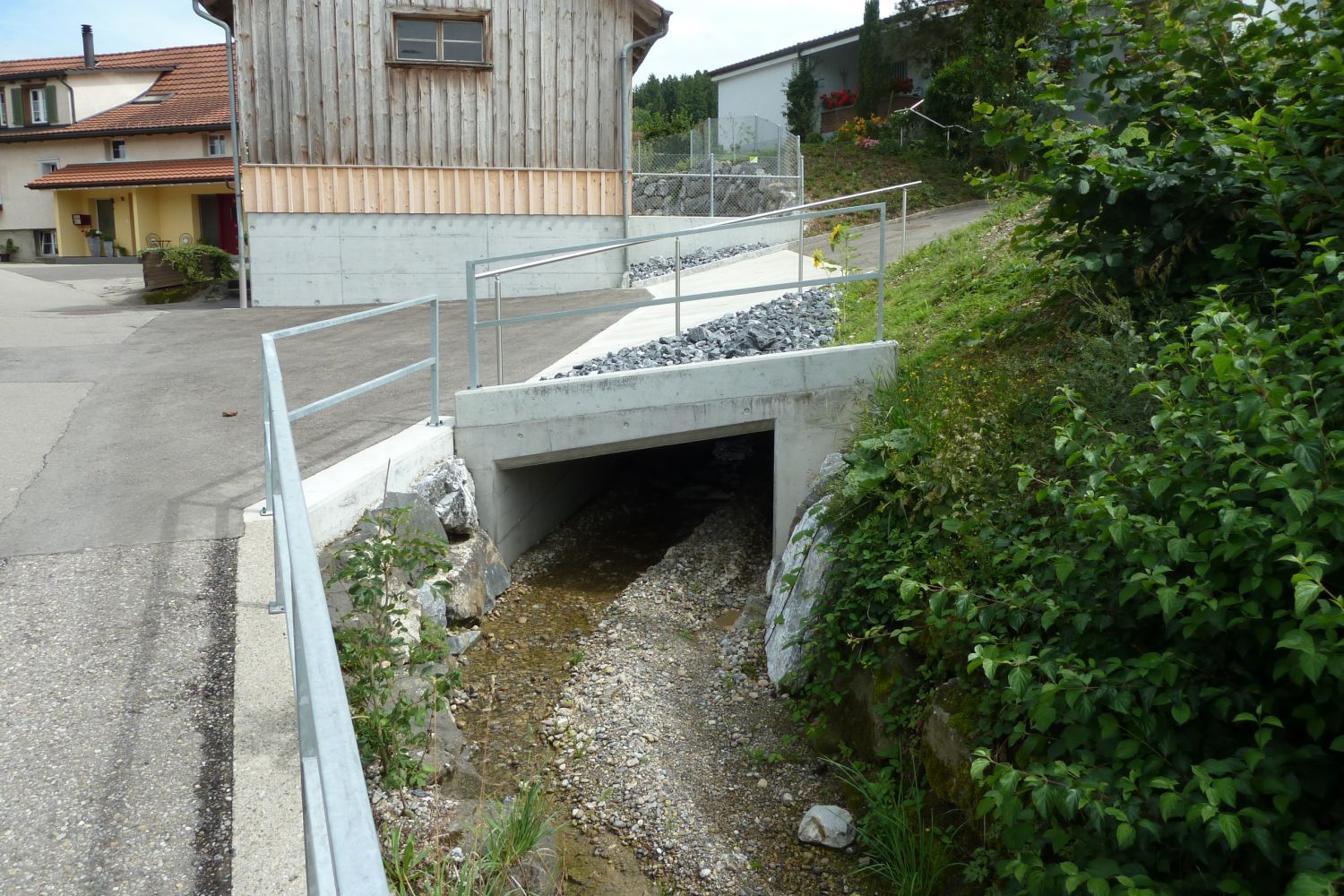 Sanierung Sonnenbergbach, Waldkirch Strasse die über einen Bach führt. Im Hintergrund steht ein Haus
