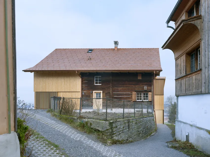 Zwei Häuser mit Holzwänden und eine Strasse im Vordergrund