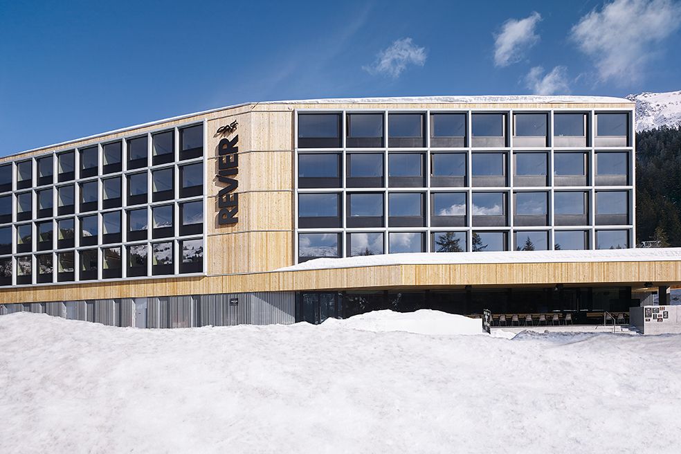 Hotel Revier, Lenzerheide Hotelgebäude mit grosser Glasfassade vor schneebedeckten Bergen