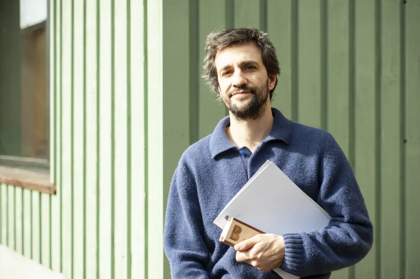 Mann vor einer Mauer mit einem Couvert in der Hand