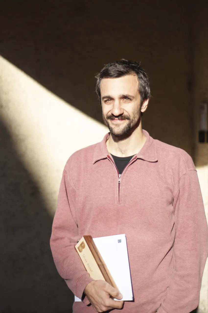 Mann vor einer Mauer mit einem Couvert in der Hand