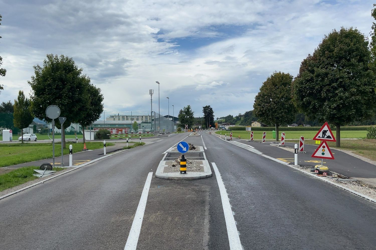 Strasse mit verschiedenen Schildern und einer Verkehrsinsel in der Mitte
